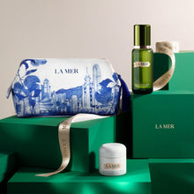Load image into Gallery viewer, A gifting suite by La Mer presented with cosmetics, a custom pouch, and a large silk scarf, all displayed on green boxes with the brand's name and logo.